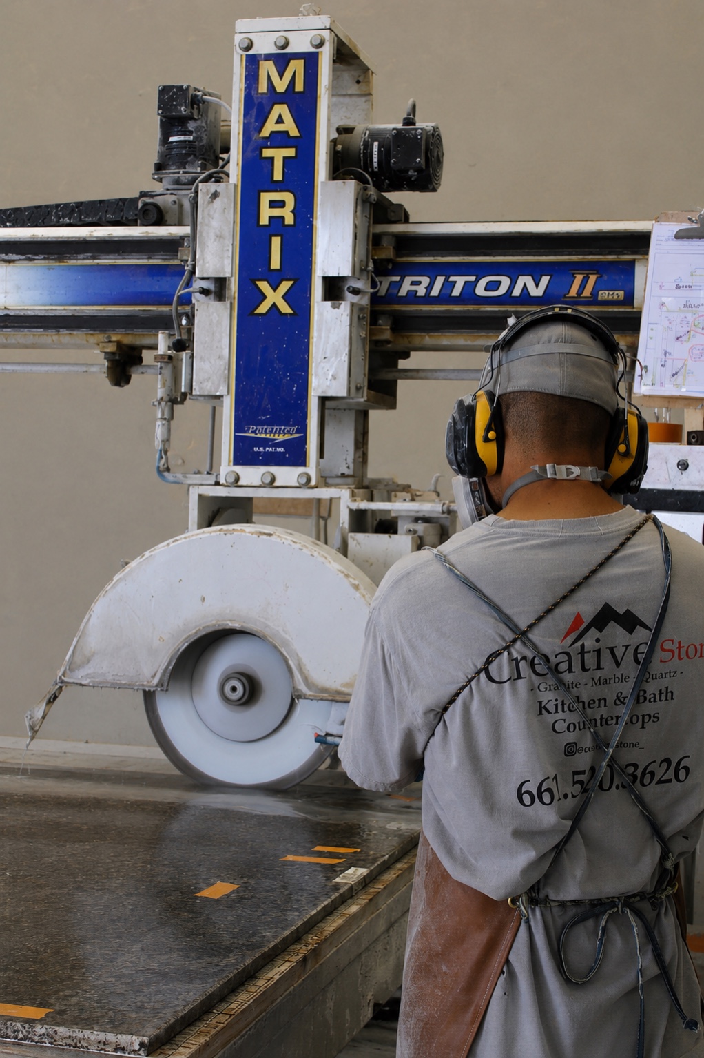 Operator running the bridge saw in the Creative Stone shop