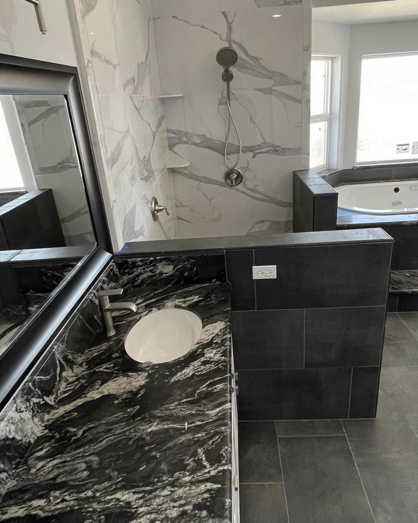 Marble slab shower walls with built-in niche and black granite vanity